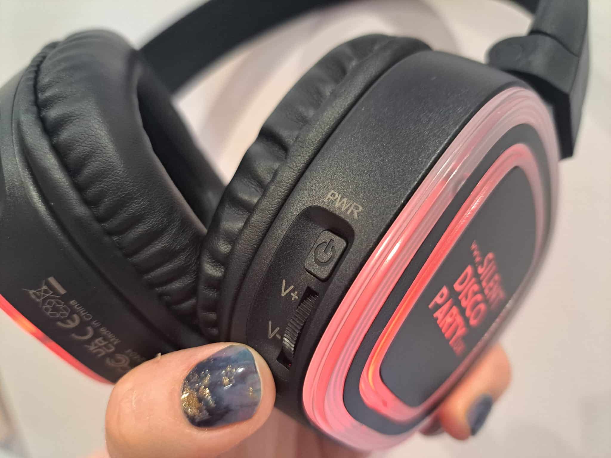 Close up of a Silent Disco Party UK wireless headphone glowing red held in hand showing the CH LED channel button