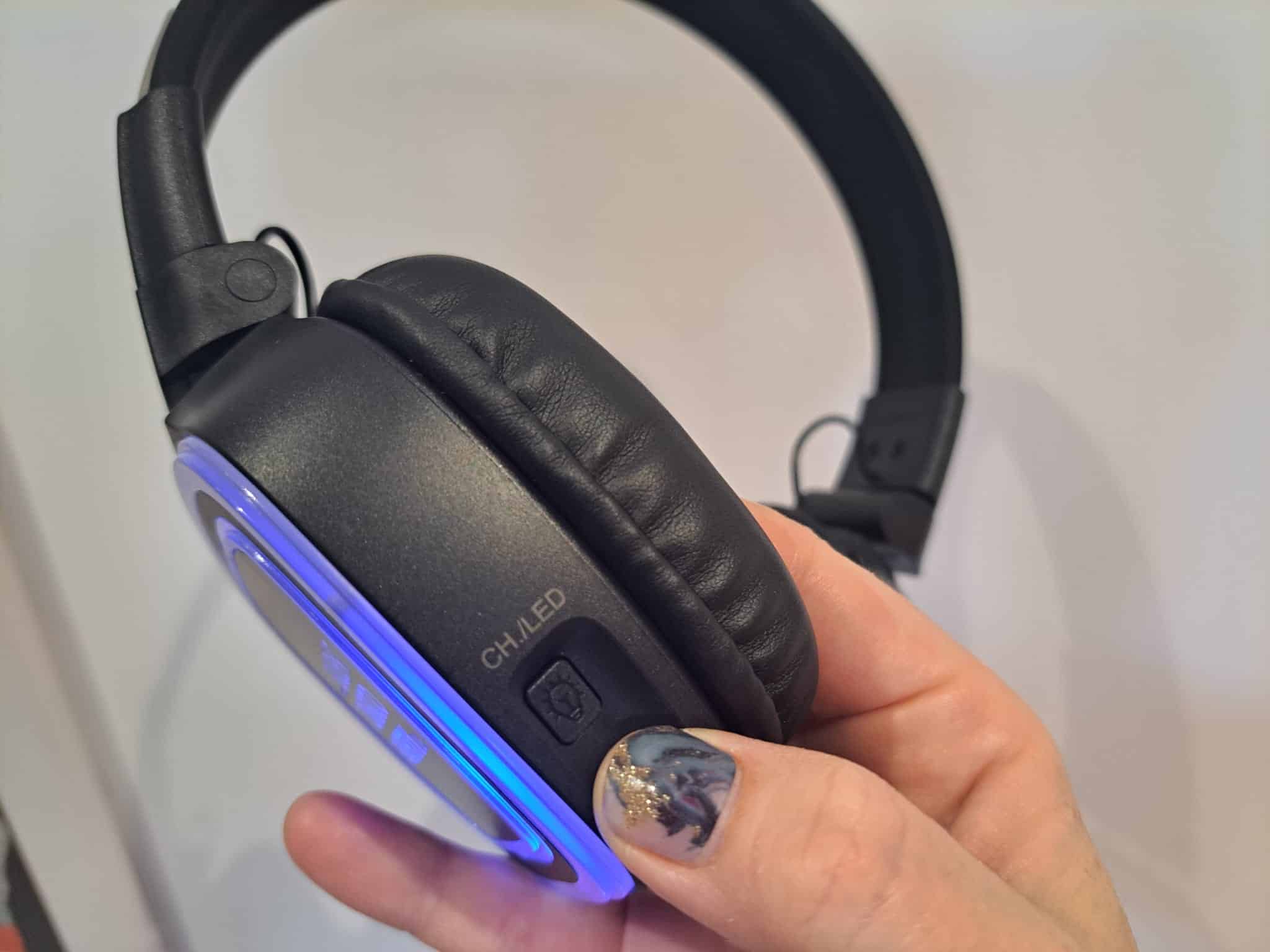 Close up of a Silent Disco Party UK wireless headphone glowing blue held in hand showing the padded ear cup and CH LED channel button
